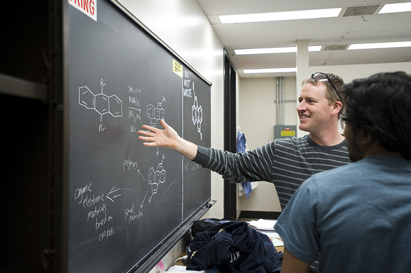 SIU Chemistry student instructs from a blackboard